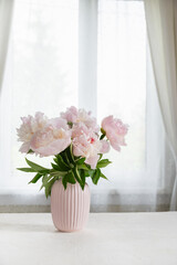 Elegant pink peonies beside the window at farm house. Slow living. Light home decoration with flowers and pink pastel vase. Bright interior. Cottagecore Aesthetics