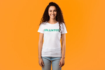 Volunteer Woman Wearing White T-Shirt Standing Smiling To Camera On Yellow Background. Female...