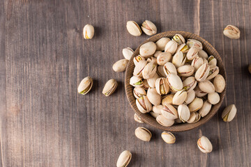 Organic roasted pistachio nuts in a wooden bowl. Top view. 