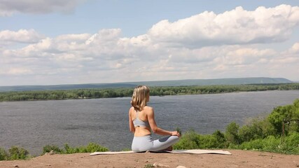 Woman wearing yoga clothes praticing yoga and stretching Sitting on a mountain over on a sunny day in nature. Healthy lifestyle concept. solo outdoor activities. - Powered by Adobe