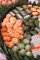 Assorted Indonesian traditionak snacks on leaf decorated with coconut leaf.