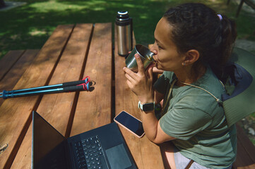 Digital Nomad Working Outdoors in a Mountain Setting with Laptop and Beverage