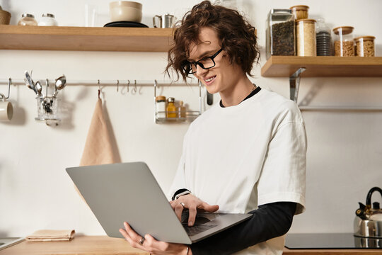 Young man enjoys a relaxed moment at home while working on his laptop in a cozy kitchen