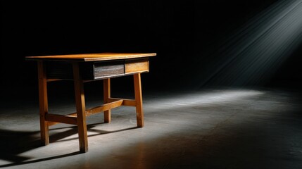 A wooden desk is sitting in a dark room with a light shining on it