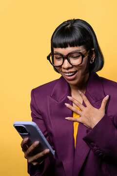Excited woman in purple blazer using smartphone