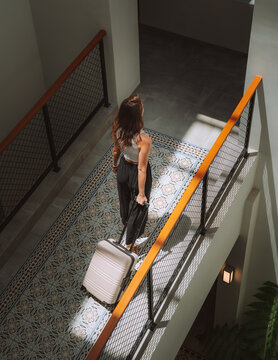 Woman walking in hotel corridor with suitcase