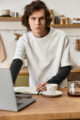 Young man enjoying a creative moment at home while sipping coffee and taking notes