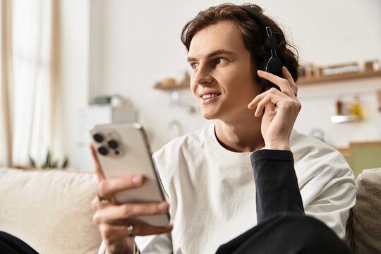 Relaxing at home a young man enjoys music while using his smartphone in casual attire - Powered by Adobe