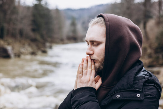 Man prays peacefully by a serene mountain river