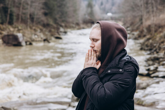 Man prays by a serene mountain river