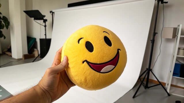 Smiley yellow emoticon with a cartoon expression, full of joy and happiness, in a kitchen or a bathroom, with a woman's hand