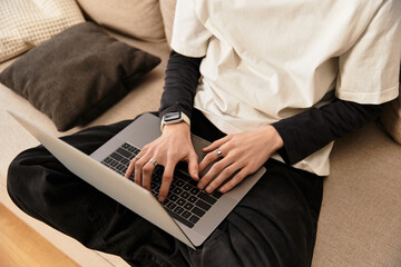 Cozy young man comfortably typing on a laptop while relaxing at home in relaxed attire