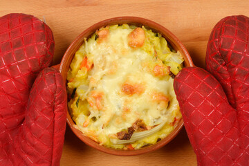 A top-down shot shows a brown oval baking dish with baked cauliflower gratin and melted cheese...