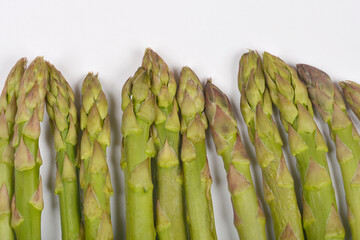 A close-up shows the tips of several fresh green asparagus spears against a plain white background