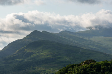Fototapeta premium moody landscape view of the Snowdonia with dramatic, heavy clouds hanging low over lush green mountains