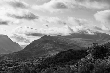 Dramatic black and white landscape showing dynamic clouds moving above and around rugged mountain...