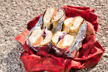 Bagels filled with smoked salmon, cream cheese, cucumber, and red onion, wrapped in aluminum foil...