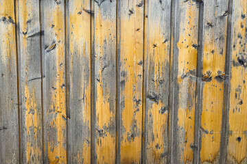 Weathered wooden wall with vertical planks in rustic yellow and gray tones