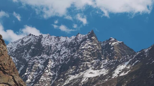 Landscape shot of clouds above snowy Himalayan mountain peak during the summer season at Jispa village in Lahaul and Spiti district, Himachal Pradesh, India. Natural mountain background in summer.