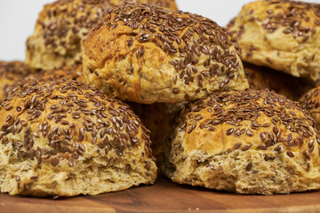 Whole grain concept. Homemade baked whole wheat rolls decorated with flaxseeds, close-up photo