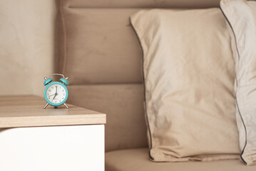 Retro turquoise alarm clock on a bedside table.