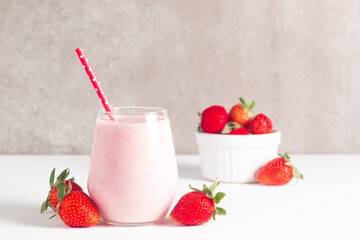 Glass of fresh strawberry milkshake, smoothie and fresh strawberries on white and wooden background. Healthy food and drink concept.
