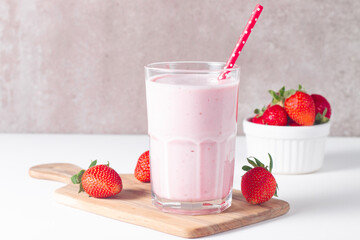Glass of fresh strawberry milkshake, smoothie and fresh strawberries on white and wooden background. Healthy food and drink concept.