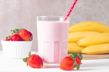 Glass of fresh strawberry milkshake, smoothie and fresh strawberries on white and wooden background. Healthy food and drink concept.