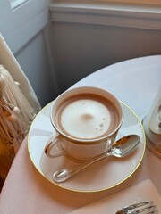 Cup of hot chocolate with milk foam served on elegant white saucer