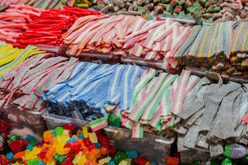 Bright sugary strips and gummy bears arranged at a colorful candy market. Highlights artificial dyes topic and the growing trend for natural coloring and clean food labels.