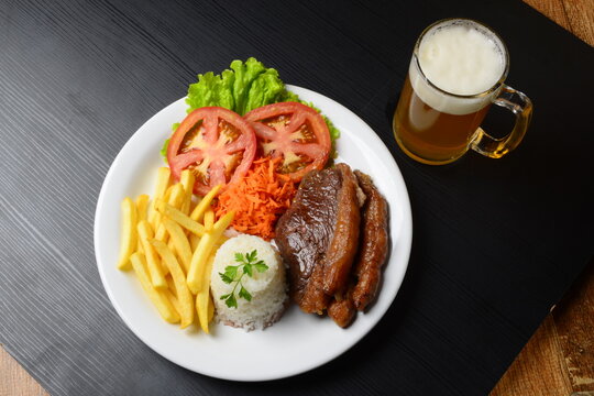Picanha grelhada servida com arroz, fritas e salada