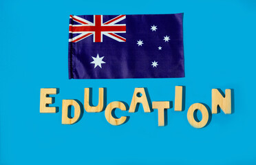 Australian flag and wooden letter word Education on blue background.