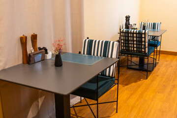 Intimate dining tables with striped chairs in cozy hotel restaurant. Contemporary interior, hospitality design, and quiet dining ambiance.