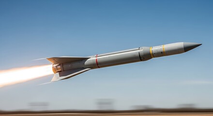A tactical guided missile flies at supersonic speed with fiery rocket propulsion during a military weapons test, showing advanced defense technology against a clear blue sky.