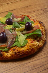 Pizza de rúcula com presunto cru e parmesão. Borda de gergelim