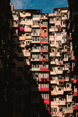 A towering, densely packed residential building in Hong Kong, with countless windows and air conditioning units, showcasing urban density