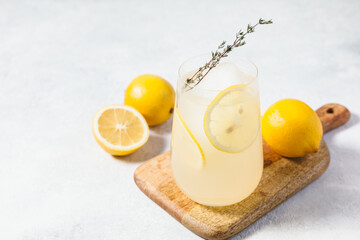 Limoncello spritz - refreshing cocktail served in a clear glass garnished with a lemon slices. The drink is placed on a wooden board next to fresh lemons, creating a summery feel and holiday vibes.