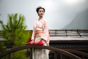 Geisha or maiko Japanese woman in traditional kimono or yukata costume holding umbrella standing at...