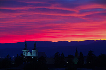 Silhouette of churches against a vibrant pink and purple sunset.