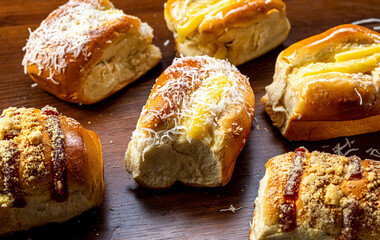 
Various sweet breads, with different flavors, made with flour, sugar, vanilla cream, guava and grated coconut, on a brown rustic table