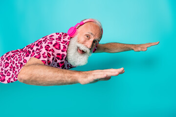 Photo of cool retired bearded male flying headphones wear trendy pink leopard print outfit isolated on aquamarine color background