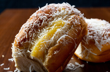 Sweet rolls with vanilla cream and grated coconut on a rustic brown wooden table and black...