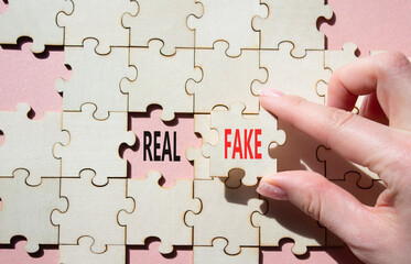 Real or Fake symbol. Concept word Real or Fake on wooden blocks. Businessman hand. Beautiful pink...