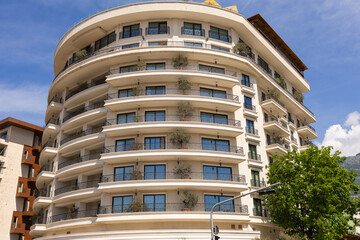 Modern apartment building with curved balconies and potted trees. Contemporary architecture, urban greenery, and residential luxury.