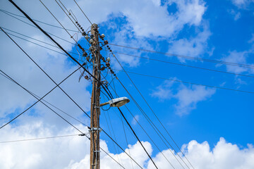 Fototapeta premium Old wooden lamp post with street light and messy electrical wires