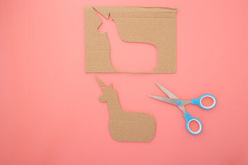 Handmade cardboard unicorn puppet used in children learning projects, ideal for educational brands, parenting media, toy shops, art schools, DIY classes, and recycled materials promotion,
