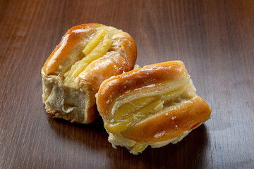 Sweet bread:
Sweet buns with vanilla cream on the brown wooden table and black background