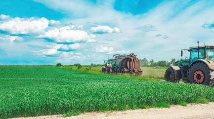 Two agricultural tractors with trailers containing tanks with organic fertilizers, manure. Tractors...