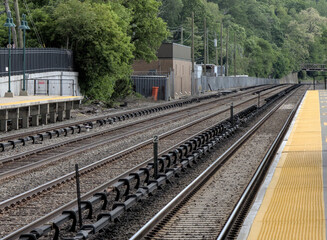 Fototapeta premium view down double train tracks on commuter rail line in upstate new york (travel commute rails track platform station stop) north metro subway