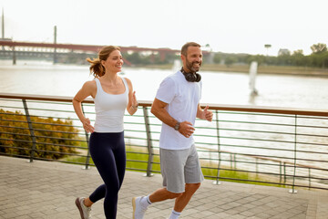 Couple enjoys a morning jog along the riverside pathway in a vibrant urban setting